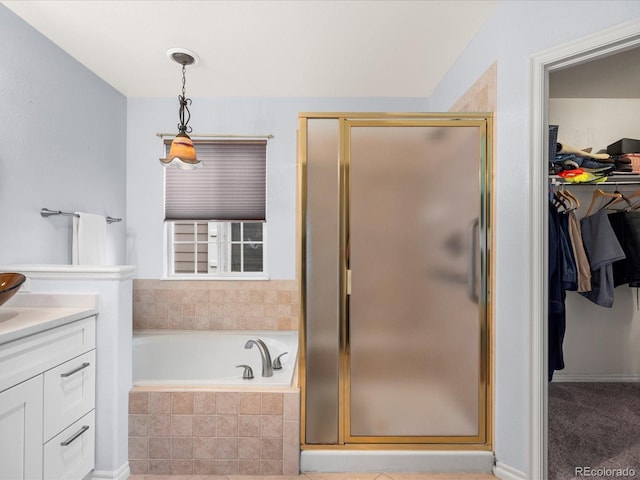full bathroom featuring vanity, a shower stall, a garden tub, and a spacious closet