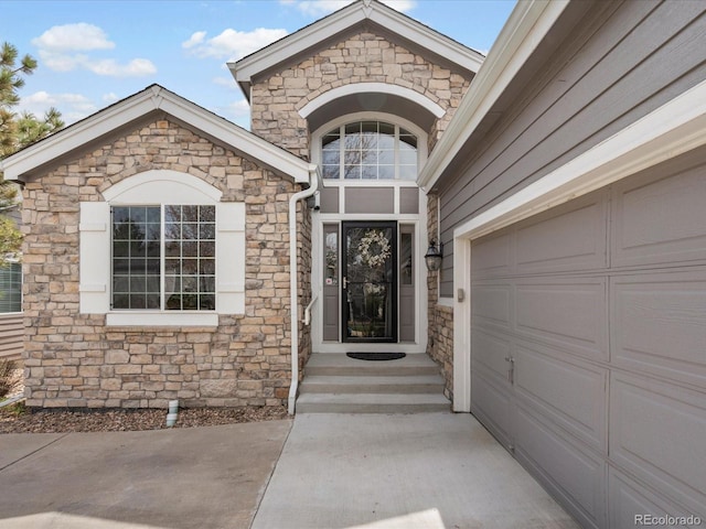 entrance to property featuring concrete driveway and stone siding