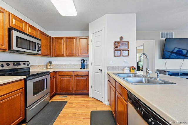 4705 Andes St, Denver, CO 80249 - kitchen with stainless steel appliances, a sink, light wood-style floors, light countertops, and brown cabinets