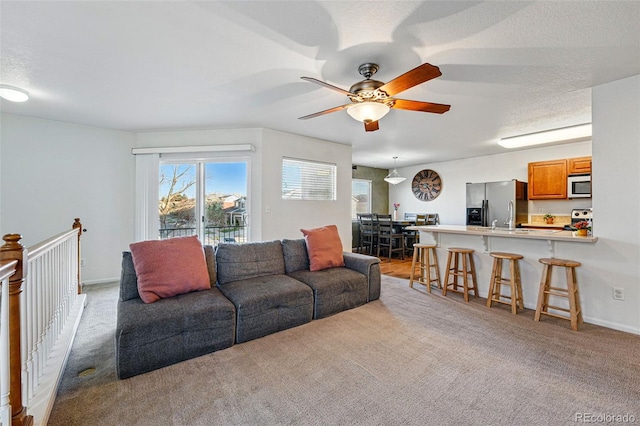 4705 Andes St, Denver, CO 80249 - living area featuring healthy amount of natural light, light colored carpet, a ceiling fan, and baseboards