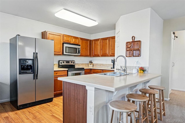 4705 Andes St, Denver, CO 80249 - kitchen with appliances with stainless steel finishes, a sink, brown cabinets, a peninsula, and a kitchen breakfast bar