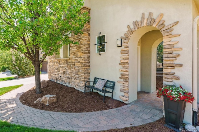 entrance to property featuring stucco siding and stone siding