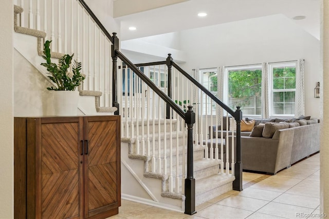 staircase featuring tile patterned flooring, recessed lighting, a high ceiling, and baseboards