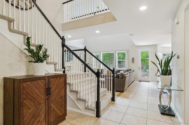 stairway featuring tile patterned flooring, recessed lighting, and a towering ceiling
