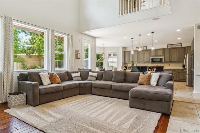 living room with a high ceiling, light wood-style flooring, and recessed lighting