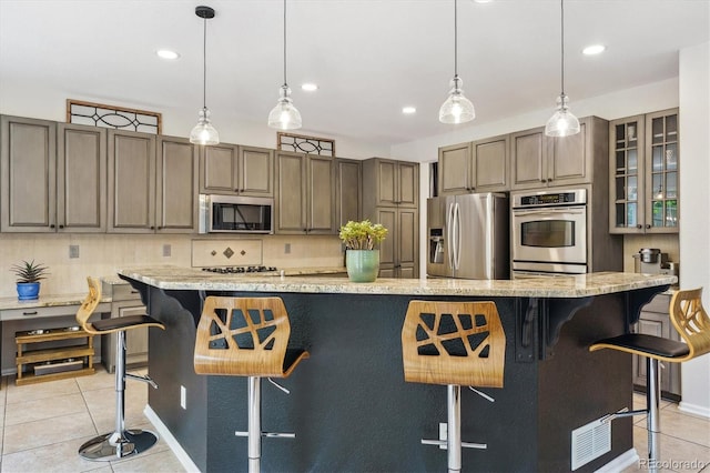 kitchen with appliances with stainless steel finishes, light tile patterned flooring, backsplash, recessed lighting, and a kitchen breakfast bar