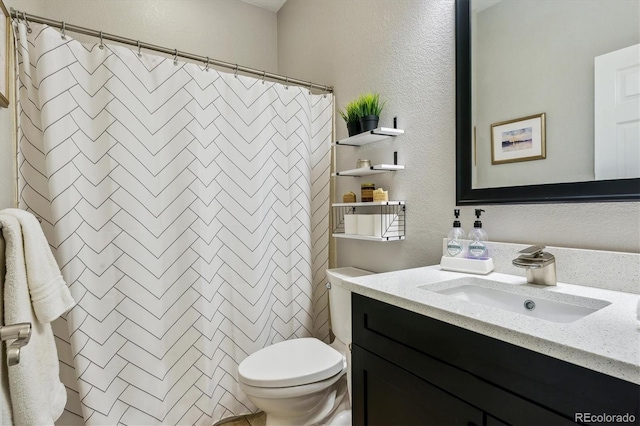 bathroom featuring toilet, a textured wall, vanity, and a shower with shower curtain