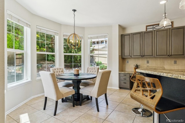 dining room featuring a chandelier, plenty of natural light, light tile patterned flooring, and baseboards