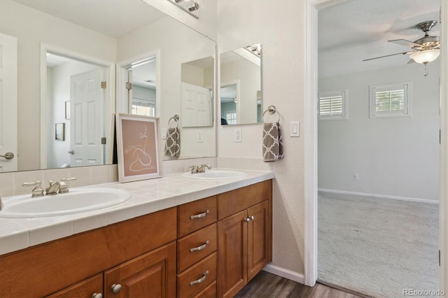 full bath featuring ceiling fan, double vanity, and baseboards