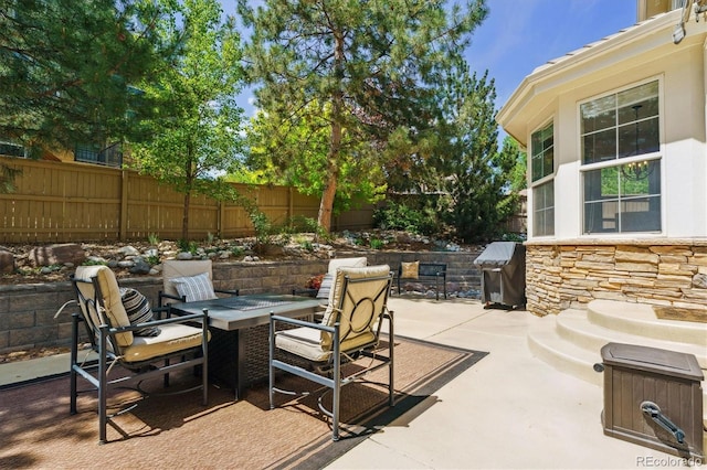view of patio featuring a fenced backyard, area for grilling, and a fire pit