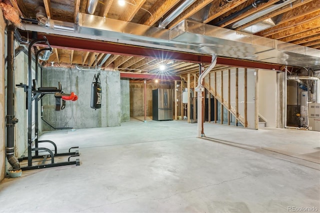 unfinished basement featuring freestanding refrigerator and stairway