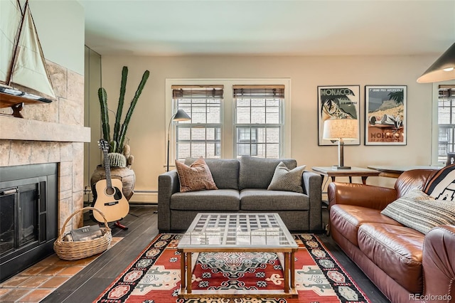 living area featuring a tiled fireplace, a baseboard heating unit, and wood finished floors