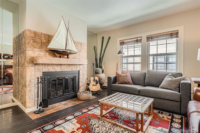 living room featuring a tiled fireplace and wood finished floors