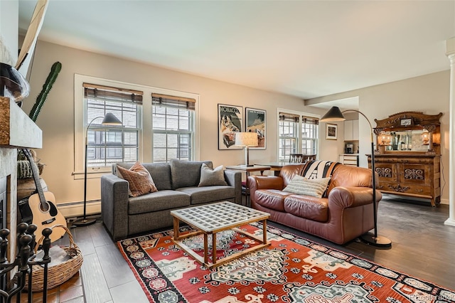 living area featuring arched walkways, wood finished floors, a healthy amount of sunlight, and baseboard heating