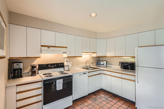 kitchen featuring a sink, light countertops, white cabinets, under cabinet range hood, and white appliances