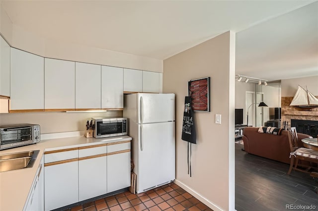 kitchen featuring freestanding refrigerator, white cabinetry, stainless steel microwave, and light countertops