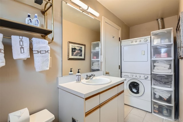 laundry area with light tile patterned floors, stacked washer / drying machine, a sink, and laundry area