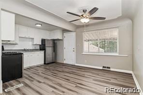 2275 S Cherokee St, Denver, CO 80223 - kitchen featuring freestanding refrigerator, white cabinets, baseboards, and a ceiling fan