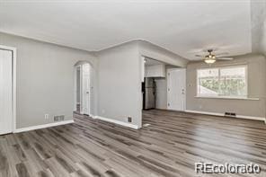 2275 S Cherokee St, Denver, CO 80223 - unfurnished living room featuring a ceiling fan, baseboards, wood finished floors, and arched walkways
