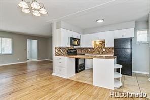 2275 S Cherokee St, Denver, CO 80223 - kitchen featuring tasteful backsplash, white cabinetry, baseboards, a chandelier, and light wood-style flooring