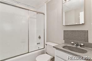 full bathroom featuring vanity, bath / shower combo with glass door, and toilet