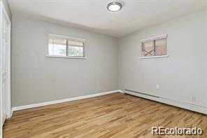 2275 S Cherokee St, Denver, CO 80223 - unfurnished bedroom featuring wood finished floors, baseboards, and a baseboard heating unit