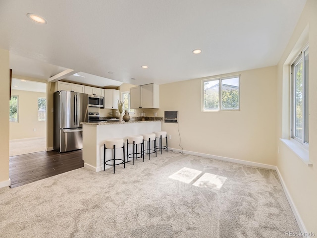 kitchen featuring stainless steel appliances, white cabinetry, kitchen peninsula, and a wealth of natural light