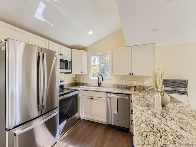 kitchen with white cabinets, sink, appliances with stainless steel finishes, light stone countertops, and vaulted ceiling