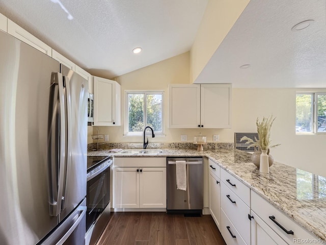 kitchen with white cabinets, vaulted ceiling, appliances with stainless steel finishes, and sink