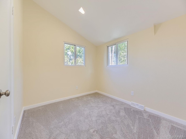 unfurnished room with light carpet, vaulted ceiling, and a healthy amount of sunlight