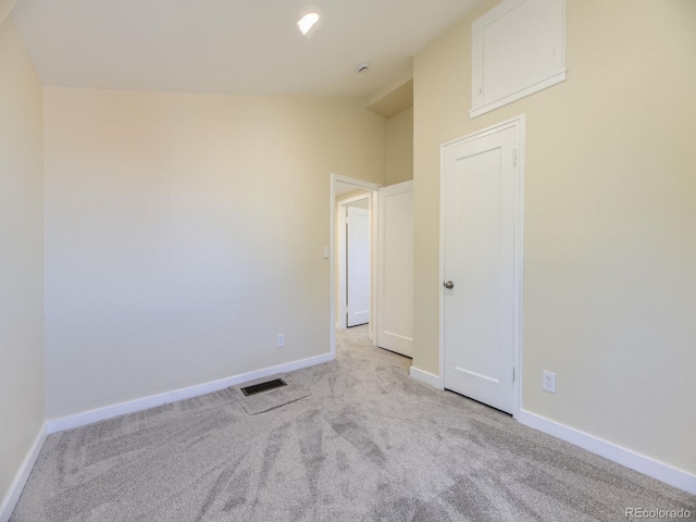 spare room featuring light carpet and lofted ceiling