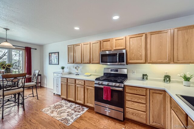 2556 E 131st Pl, Thornton, CO 80241 - kitchen featuring appliances with stainless steel finishes, light countertops, light wood-type flooring, decorative light fixtures, and recessed lighting
