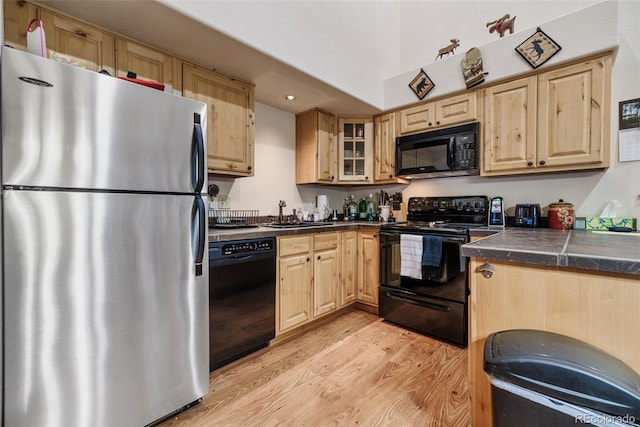2150 Michigan Hill Rd, Jefferson, CO 80456 - kitchen featuring black appliances, light brown cabinets, light wood-style flooring, a sink, and glass insert cabinets