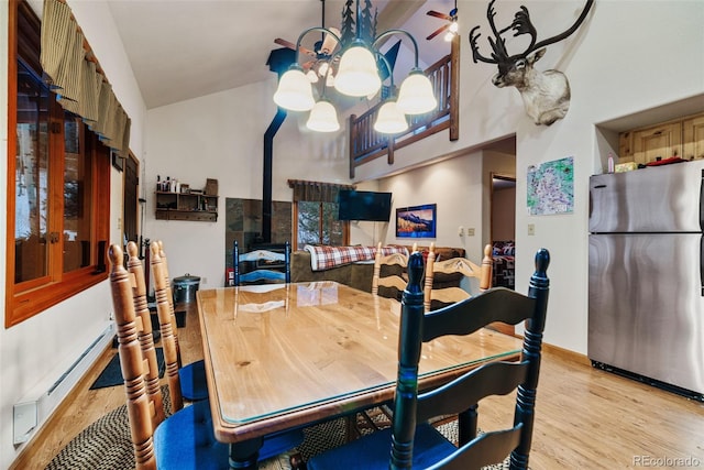 2150 Michigan Hill Rd, Jefferson, CO 80456 - dining area featuring a chandelier, light wood-style floors, a baseboard radiator, and a towering ceiling