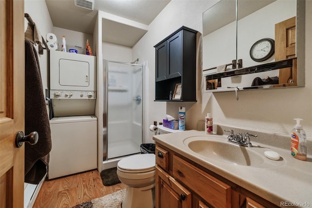 2150 Michigan Hill Rd, Jefferson, CO 80456 - bathroom featuring estacked washer and dryer, wood finished floors, a shower stall, and toilet
