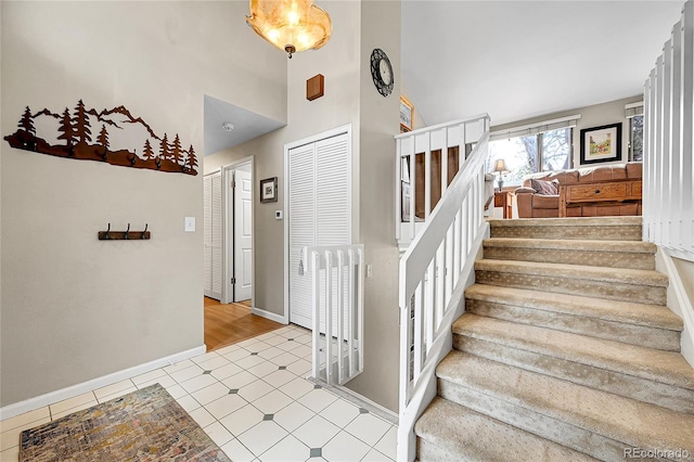 stairway featuring a towering ceiling and baseboards