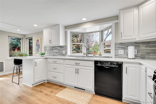 kitchen with white cabinets, a peninsula, a sink, and black dishwasher