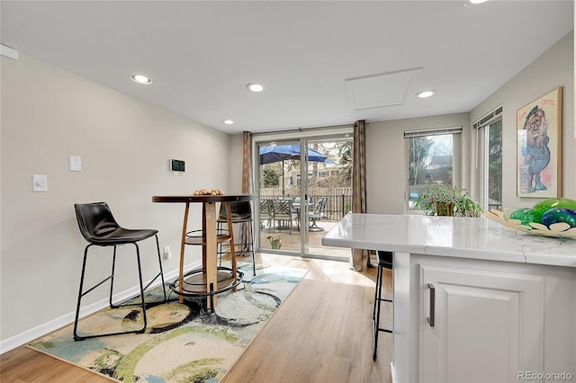 dining area featuring baseboards, light wood-type flooring, attic access, and recessed lighting