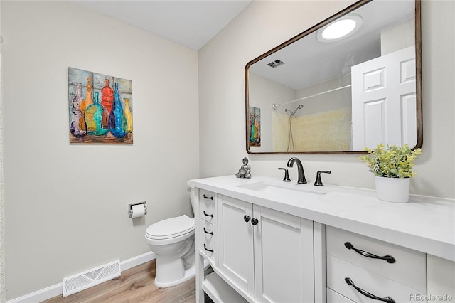bathroom featuring visible vents, baseboards, toilet, vanity, and wood finished floors