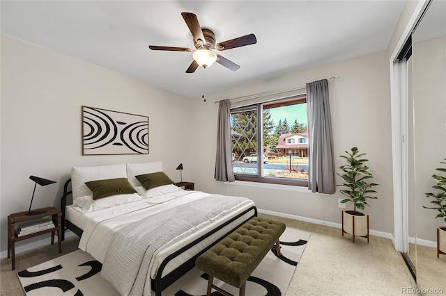 bedroom featuring baseboards, light colored carpet, and ceiling fan