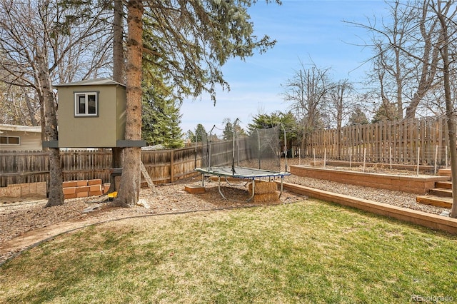 view of yard with a fenced backyard, a vegetable garden, and a trampoline