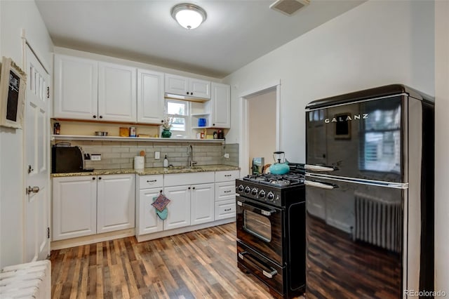 kitchen with sink, dark hardwood / wood-style flooring, decorative backsplash, white cabinets, and black appliances