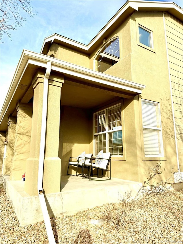 view of side of home featuring covered porch and stucco siding