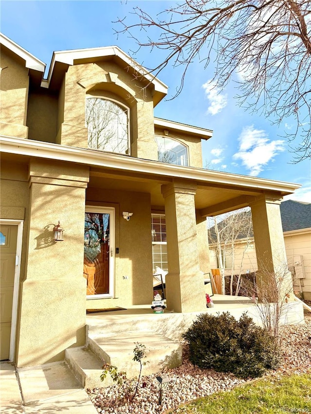 property entrance with covered porch and stucco siding