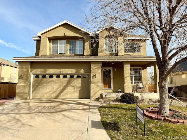 traditional-style home featuring covered porch, driveway, fence, and stucco siding