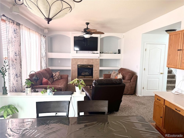 carpeted living area featuring ceiling fan, a fireplace, stairs, and built in features