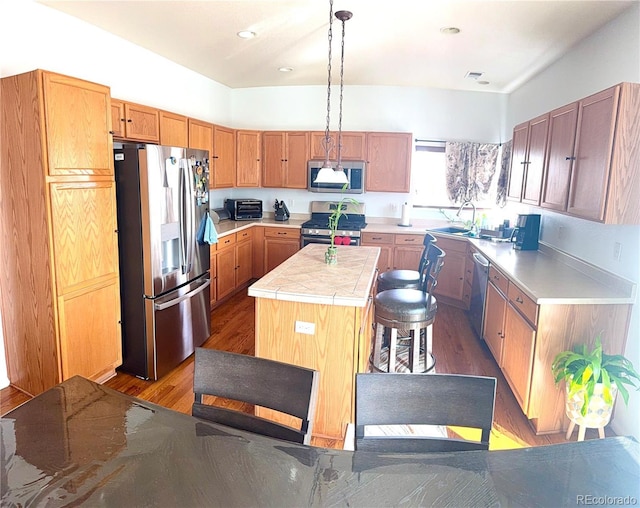 kitchen featuring a center island, visible vents, appliances with stainless steel finishes, a sink, and wood finished floors