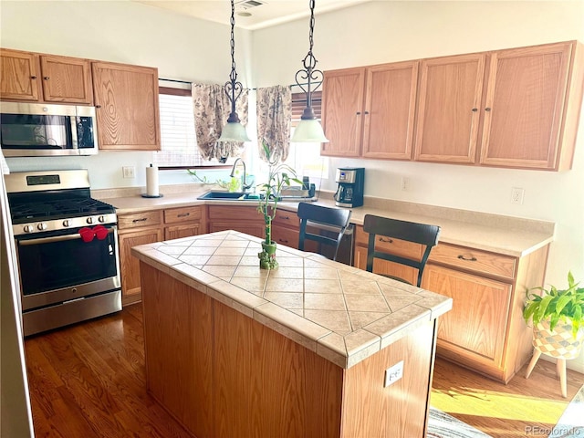 kitchen featuring a center island, dark wood-style flooring, decorative light fixtures, appliances with stainless steel finishes, and a sink