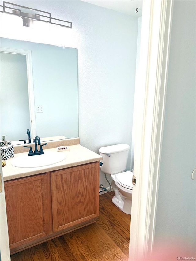 bathroom featuring toilet, wood finished floors, and vanity