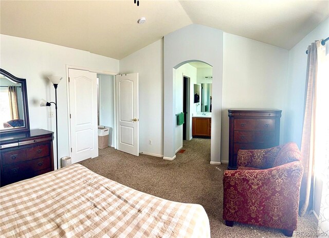 bedroom featuring carpet floors, arched walkways, lofted ceiling, connected bathroom, and baseboards